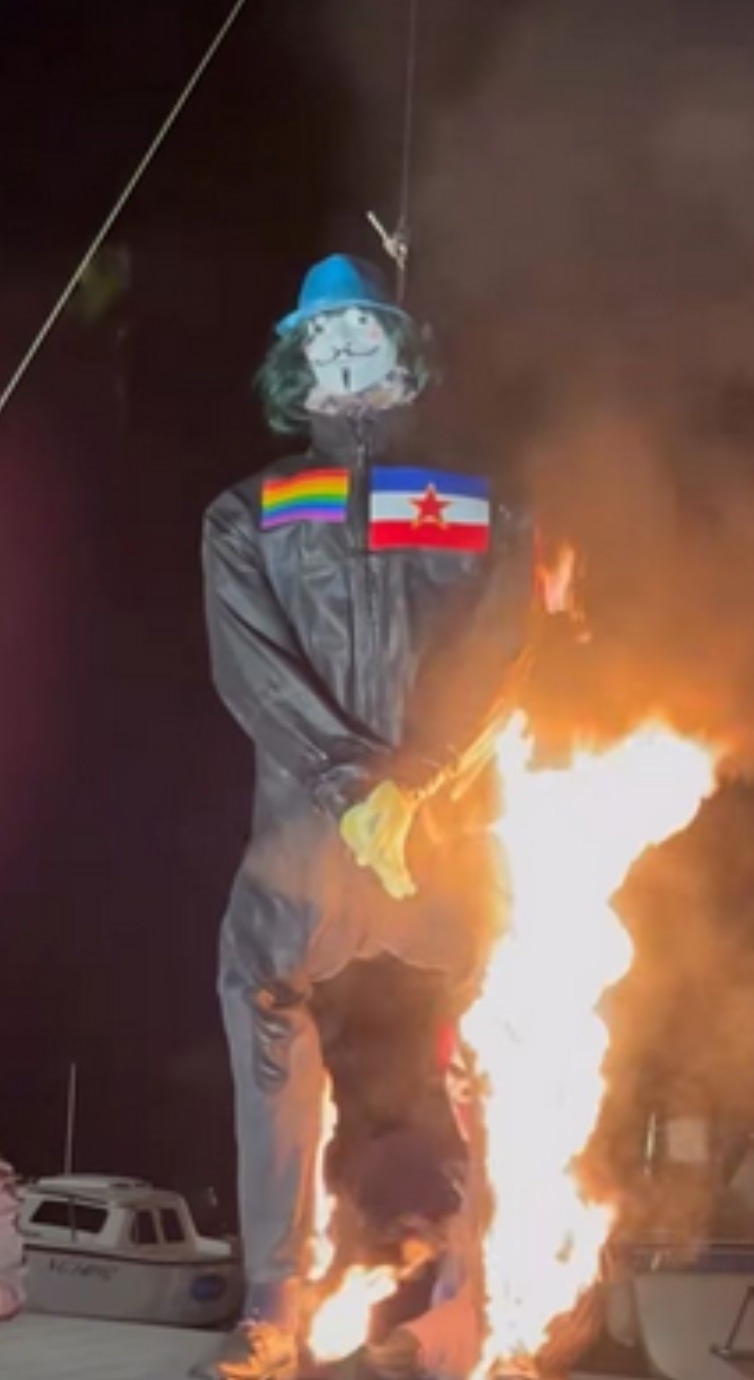 Lutka krnje u crnom s maskom, LGBT zastavom i zastavom Jugoslavije na lomači u Novigradu.